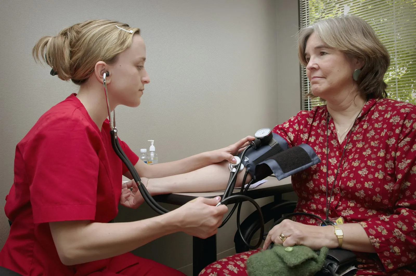 A nurse measuring a woman's blood pressure with a cuff and stethoscope
